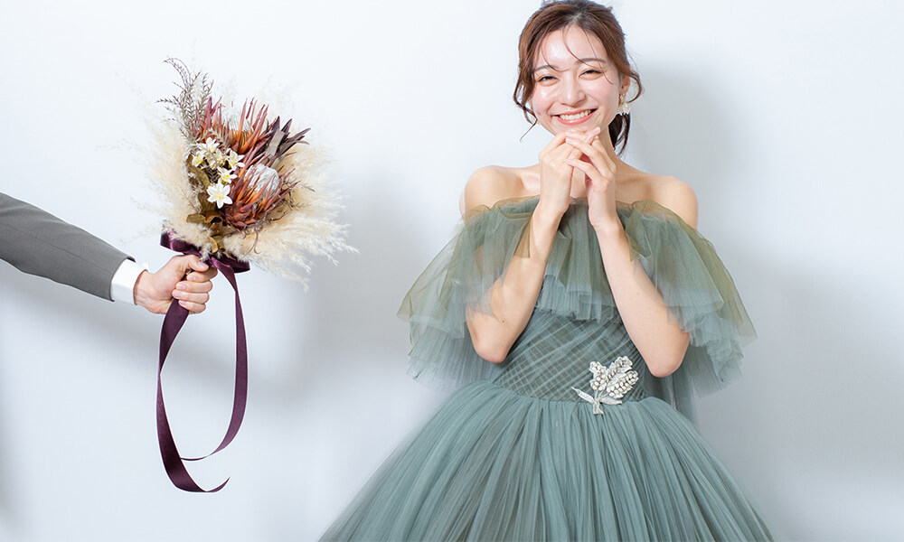 「マイブライド一宮」のスタジオで花嫁にドライフラワーの花束を差し出す洋装フォトのイメージ