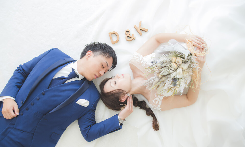 「マイブライド清洲」のスタジオで互いになって横たわる洋装フォトを撮影する花嫁と新郎のイメージ