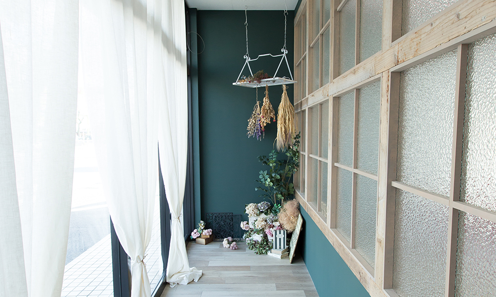 深い緑色の壁面に、ドライフラワーや雑貨が設置された北欧テイストの「マイブライド岡崎北」のスタジオイメージ