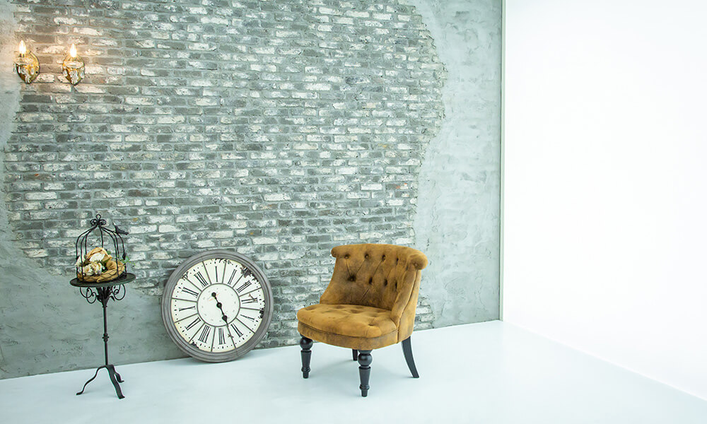 雰囲気のあるレンガの壁の前に、洋風な椅子や時計を配置したレトロな雰囲気の「マイブライド尾張旭」のスタジオイメージ